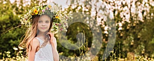 Cute smiling little girl  with flower wreath on the meadow at the farm. Portrait of adorable small kid outdoor