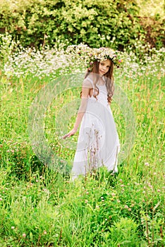 Cute smiling little girl  with flower wreath on the meadow at the farm. Portrait of adorable small kid outdoor