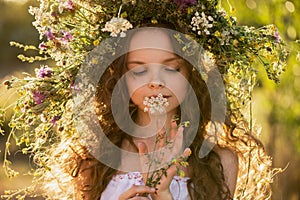 Cute smiling little girl  with flower wreath on the meadow at the farm. Portrait of adorable small kid outdoor