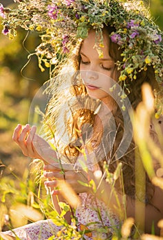 Cute smiling little girl  with flower wreath on the meadow at the farm. Portrait of adorable small kid outdoor