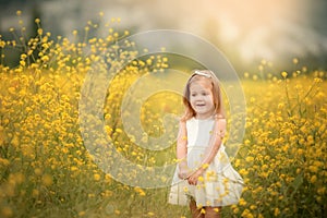 Cute smiling little girl with flower wreath on the meadow at the farm. Portrait of adorable small kid outdoors