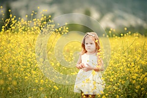 Cute smiling little girl with flower wreath on the meadow at the farm. Portrait of adorable small kid outdoors