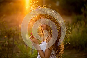 Cute smiling little girl with flower wreath on the meadow at the farm. Portrait of adorable small kid outdoors. Midsummer