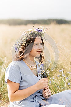 Cute smiling little girl with flower wreath on the meadow. Portrait of adorable small kid outdoors