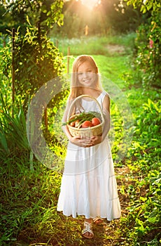 Cute smiling little girl holds basket with fruit and vegetables