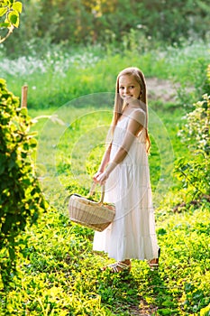 Cute smiling little girl holds basket  with fruit and vegetables at the farm