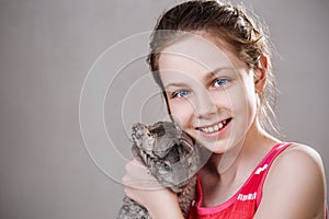 Cute smiling little girl holds funny gray chinchilla.