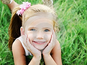 Cute smiling little girl lying in grass