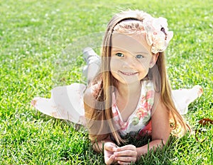 Cute smiling little girl lying on grass