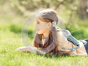 Cute smiling little girl lying on the grass