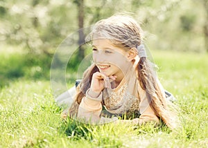 Cute smiling little girl lying on the grass