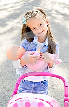 Cute smiling little girl playing with her toy carriage