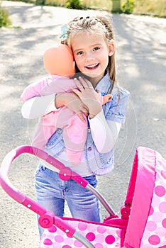 Cute smiling little girl playing with her toy carriage