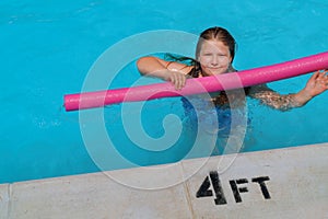 Cute smiling little girl in summer vacation swimming pool