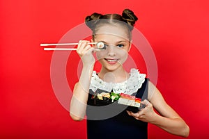 Cute smiling little girl with with sushi on  red background