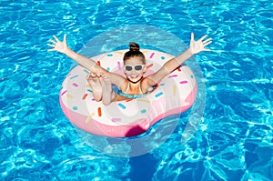 Cute smiling little girl in swimming pool with rubber ring