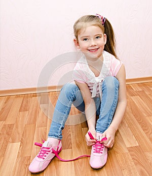 Cute smiling little girl tying her shoes