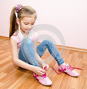 Cute smiling little girl tying her shoes