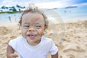 Cute smiling mixed race little boy playing at the beach