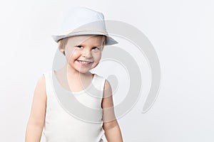 Cute smiling summer boy in white shirt and hat on white background. Shirt mockup, summer child fashion