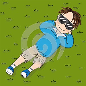 Cute smiling teenage boy with black sun glasses lying, resting and day dreaming on the green grass in the park or on the lawn