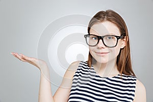 Cute smiling teenage girl in glasses holding copyspace on palm