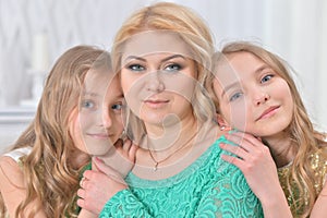 Cute smiling twin sisters hugging their mother