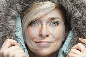 Cute smiling woman in a hood with fur. Beauty and fashion in the cold season. Close-up