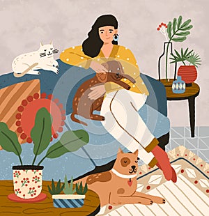 Cute smiling young girl sitting on comfy sofa with dogs and cat. Adorable woman spending time at home with her domestic