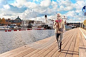 Cute stylish and trendy girl walking on pier in Stockholm. photo