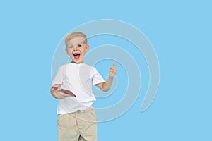 Cute smilling child boy with smartphone on blue background. Advertising of educational applications on a mobile