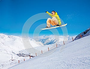 Cute snowboarder man jumping on ski resort