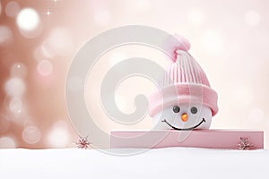 A cute snowman peek out of blank banner on blurred peach fuzz background. Winter holiday banner for Christmas greetings