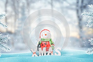 Cute snowman in Santa Claus clothes in New Year, Christmas glass magic ball. Snow fall on it and Christmas tree beside