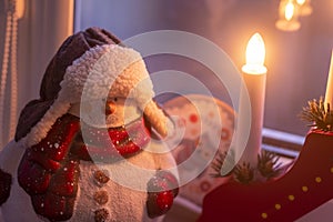 Cute snowman toy in a hat and Christmas decorative lamp