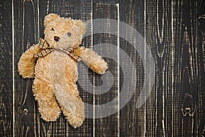 Cute soft brown teddy bear laying on wooden shabby background