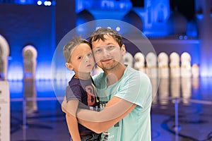 Cute son and father dreaming at the grand mosque of Sheikh Zayed Mosque in Abu Dhabi wearing abaya, paranja in night time. Travell