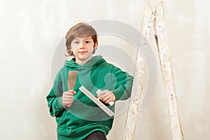 Cute son helps parents to repair room. Kid with tools. New house for family