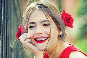 Cute spanish teen girl with red lips and roses in hair. Happy face.