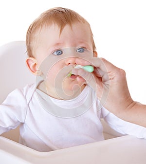 Cute, spoon and baby eating vegetables in feeding chair in a studio for health and nutrition. Sweet, natural and boy