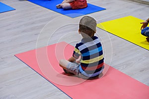 Cute sporty kid exercising on yoga mats in gym, children sport school concept