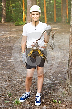 Cute, sporty young boy in helmet and white t shirt in the rope adventure park in the summer. Active sport life