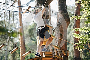 Cute, sporty, young boy in white t shirt in the adventure activity park with helmet and safety equipment. Young boy