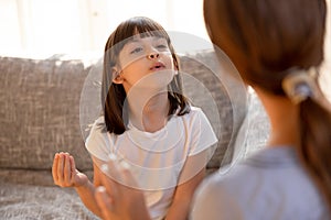 Cute stuttering child girl speaking doing exercises with speech therapist photo