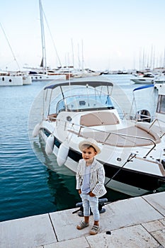 Cute stylish boy posing near yacht in marina