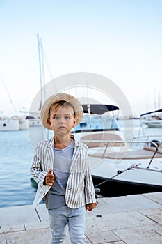 Cute stylish boy posing near yacht in marina