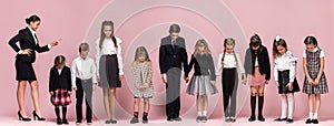 Cute stylish children on pink studio background. The beautiful teen girls and boy standing together