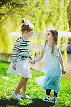 Cute stylish little girls playing at park outdoor