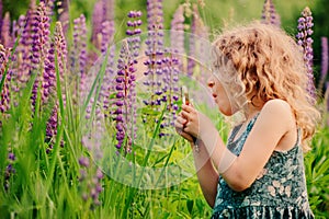 Cute surprised child girl exploring nature with loupe on summer field