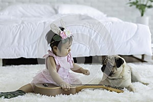 Cute Sweet Adorable Asian Baby wearing white dress Sitting on white bed smiling and playing with dog
